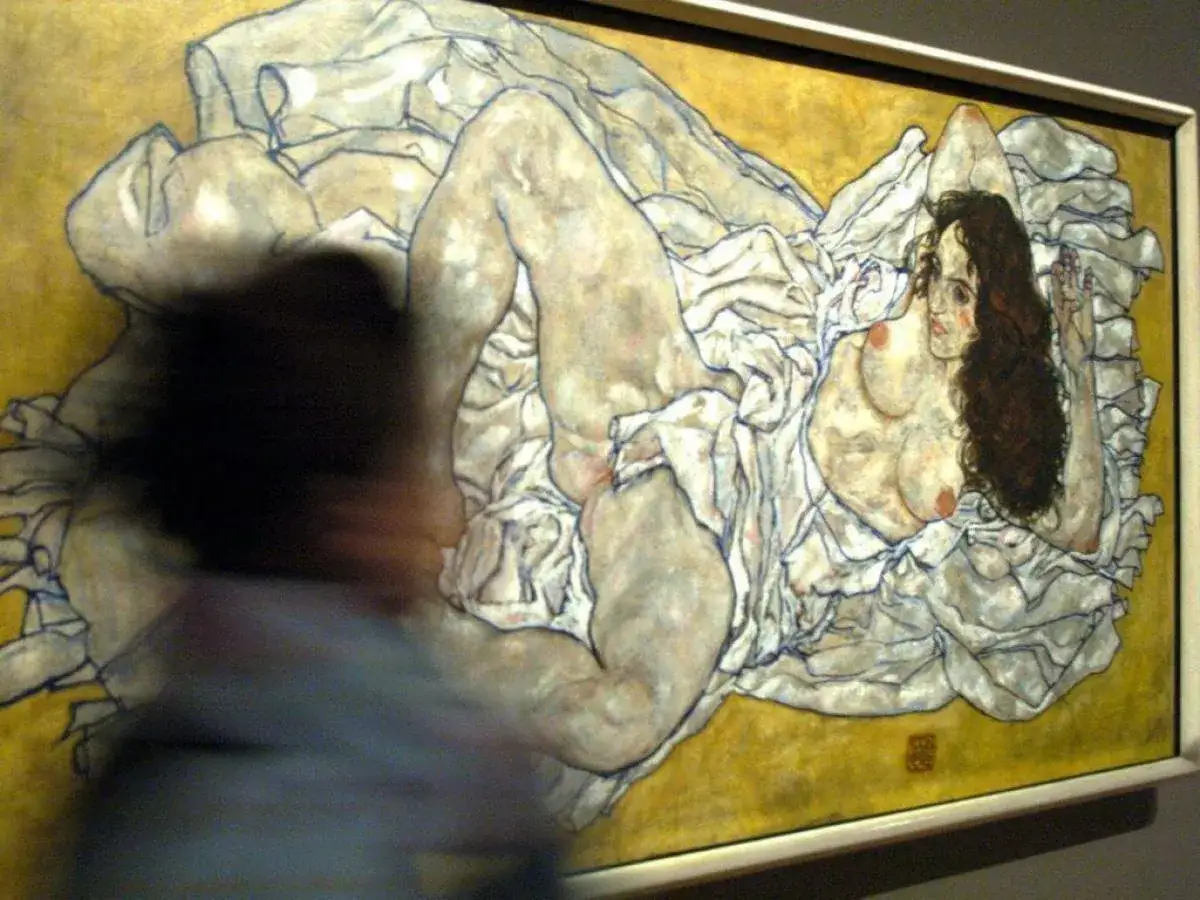Une femme nue, peinte par le peintre Schiele, est allong&eacute;e sur des draps blancs froiss&eacute;s, son corps expressif captur&eacute; dans un style audacieux.